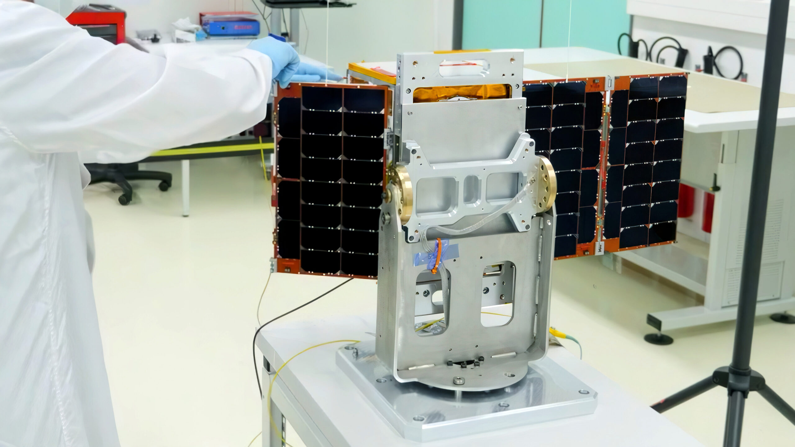 Close-up of an engineer showing a small high-tech satellite in the factory.